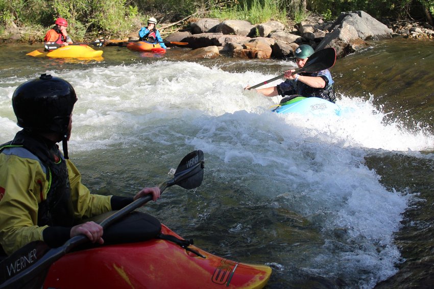 Grant Kashner, far right, moves into the kayaking feature, called "the rodeo hole," as his fellow competitors look on during the June 22 Kayak Rodeo at Clear Creek Whitewater Park.